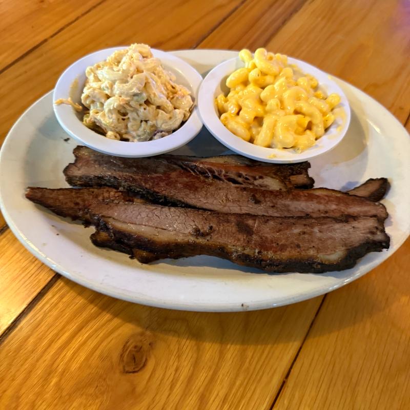Sliced smoked brisket with macaroni salad and mac and cheese