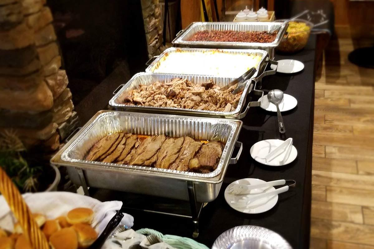 A catering buffet of smoked meats in chafing dishes