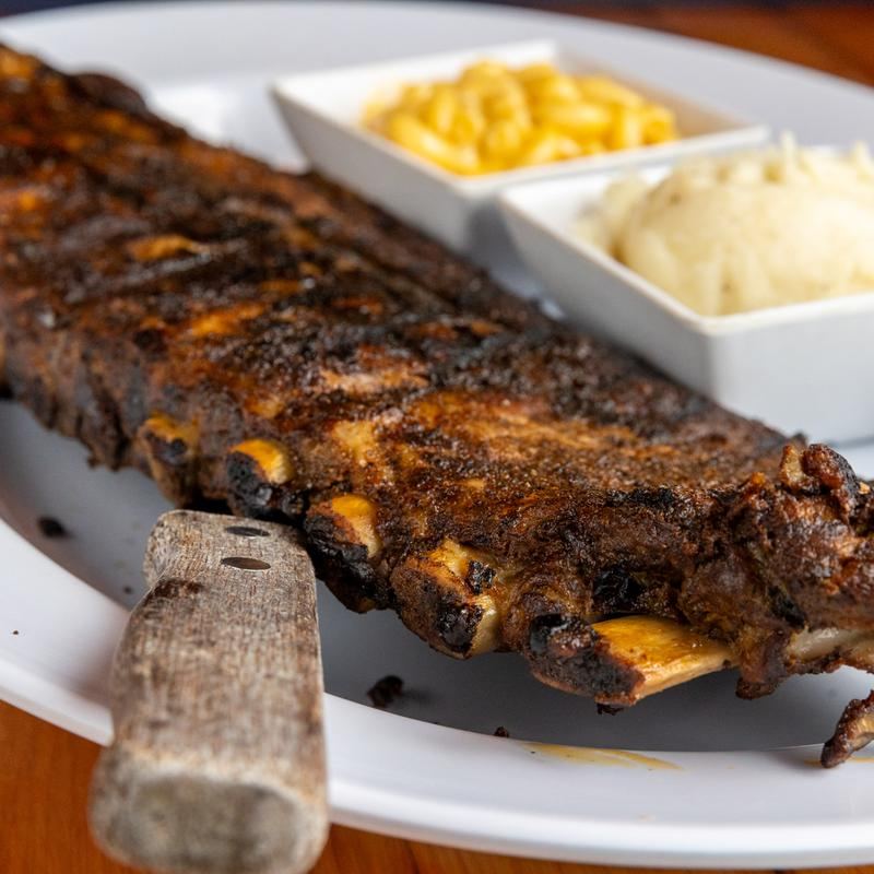 A rack of dry-rubbed smoked ribs with mac and cheese and mashed potatoes